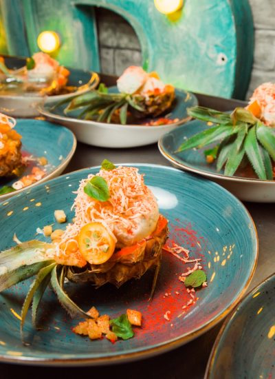Freshly prepared salad lies inside the pineapple, which is cut lengthwise, sprinkled with grated cheese. Everything looks very appetizing.